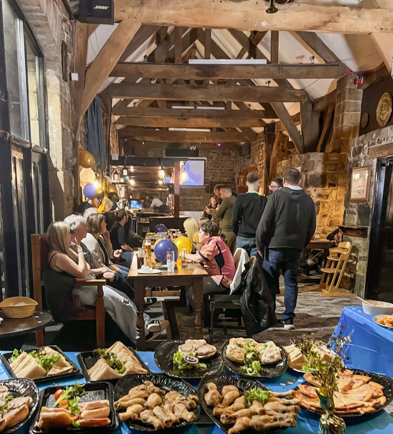 Catering Service A rustic dining setting with people enjoying food and drinks at wooden tables.